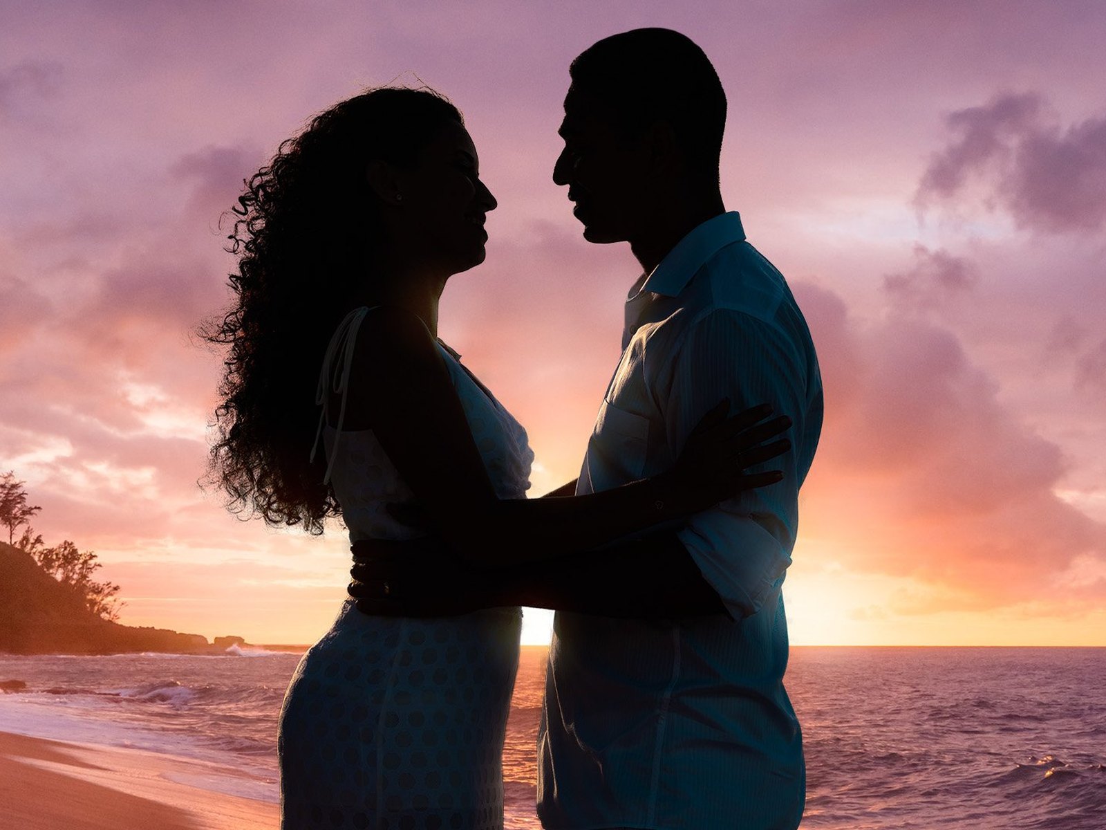 A couple embracing in silhouette on a beach at sunset